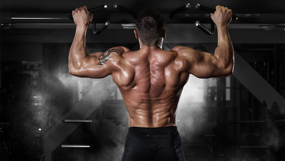 muscular guy with a tatoo doing pull ups with strong lats