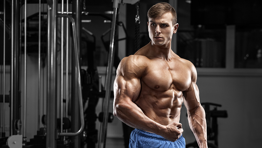 Muscular Guy in Blue Shorts Flexing In Front of a Mirror